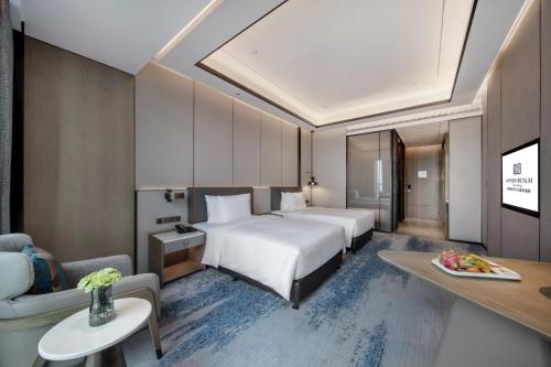 a hotel room with two beds and a couch at Wanda Realm Kunming in Kunming
