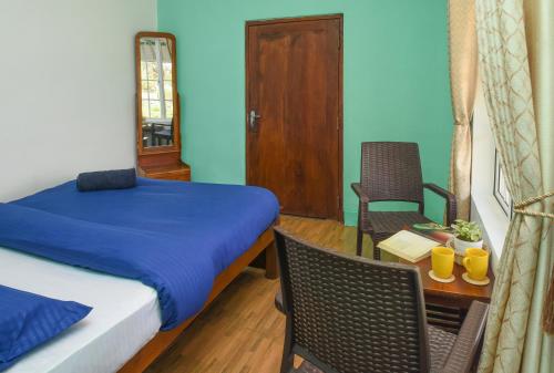 a bedroom with a bed and a table and chairs at Gregory House Hostel in Nuwara Eliya