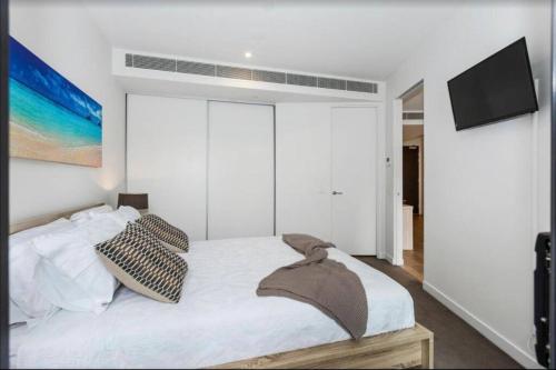 a white bedroom with a bed and a flat screen tv at Sandy Hill apartment, Sandringham in Sandringham