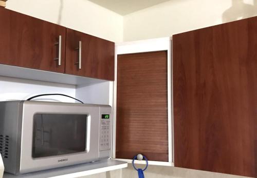 eine Küche mit einer Mikrowelle und Holzschränken in der Unterkunft Hogar dulce hogar in Mexiko-Stadt