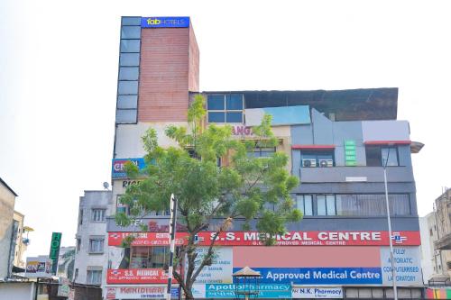 um edifício alto numa rua da cidade com uma árvore em FabExpress Sunrise em Ahmedabad