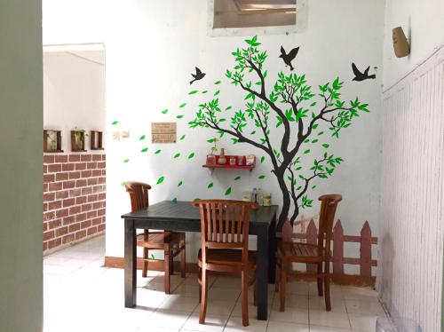 a table with a tree and birds on a wall at Garser in Yogyakarta