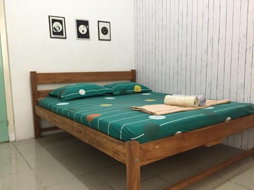 a bed with green sheets and pillows on it at Garser in Yogyakarta