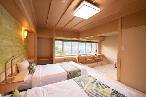 two beds in a room with a window and a table at Fuji Lake Hotel in Fujikawaguchiko