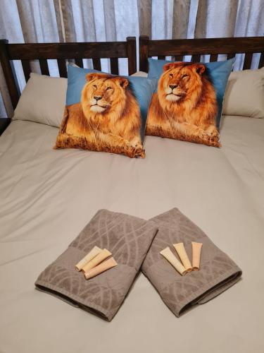 a bed with two lion pillows and two towels at Huis Afrika in Vanderbijlpark