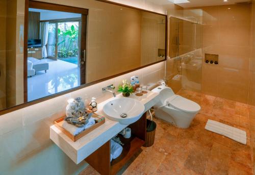 a bathroom with a sink and a toilet and a mirror at Kahayana Seminyak Villa in Seminyak