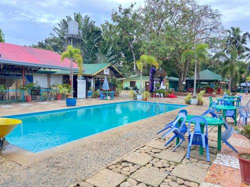 a swimming pool with blue chairs and a playground at Angela's Pool Resort in Puerto Princesa City