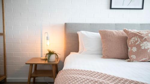 a bed with pink and white pillows and a table at 8 on Clarence in Moss Vale