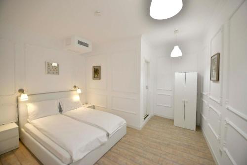 a white bedroom with a bed and a refrigerator at Otilia in Bucharest