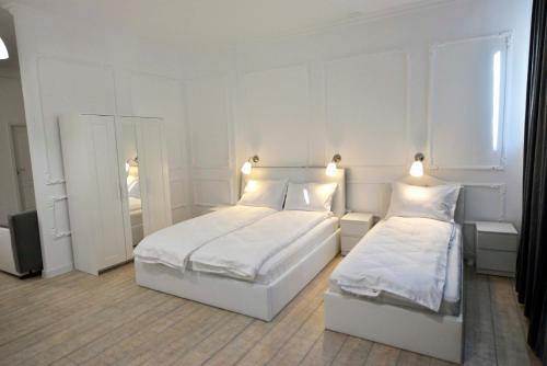 a white bedroom with two beds and a mirror at Otilia in Bucharest