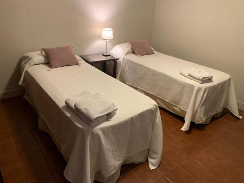 two beds in a room with white sheets at Los Naranjos Departamentos 2 in Concepción