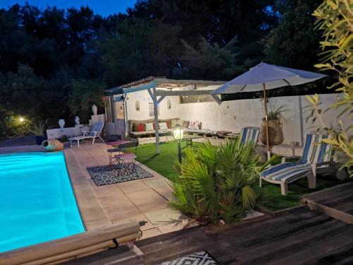 un cortile con piscina e ombrellone di Villa Chiara a Magalas