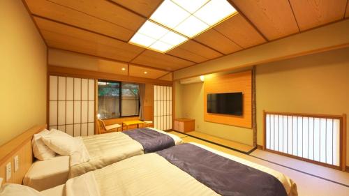a large room with two beds and a television at Kagiya in Minamiizu
