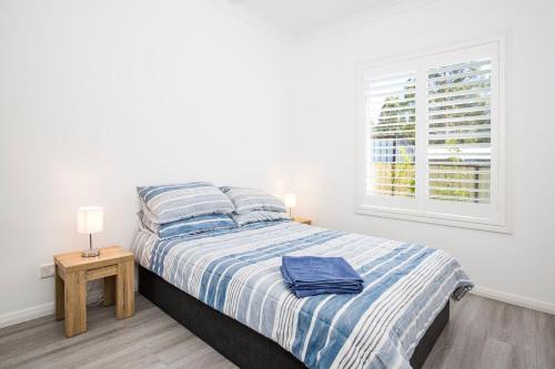 a white bedroom with a bed and a window at Sanctuary Blue Pet Friendly 5 Mins to Hyams Beach in Sanctuary Point
