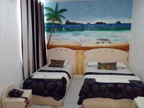 two beds in a room with a painting of the beach at Euro Vacances Guest House in Roches Brunes