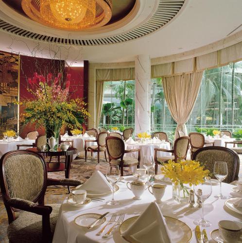 a dining room with white tables and chairs and windows at Shangri-La Singapore in Singapore