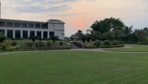 a large building with a grass field in front of it at The Greenwood, Tezpur in Tezpur