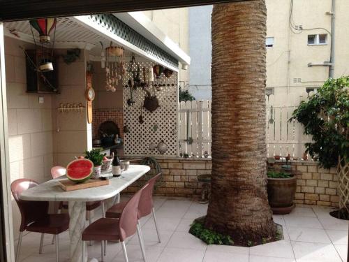 a table and chairs on a patio with a tree at Alona's Apartments - Beach Apartment in Haifa