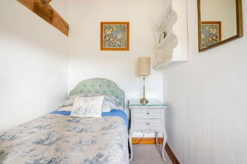 a small bedroom with a bed and a night stand at Coach House - detached cottage within 135 acres in Bromyard