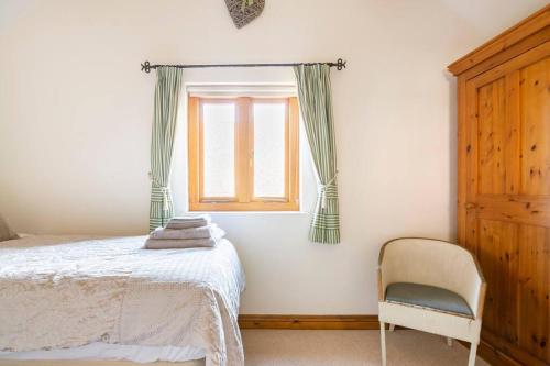 a bedroom with a bed and a chair and a window at Coach House - detached cottage within 135 acres in Bromyard