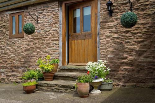 a stone house with potted plants in front of a door at Coach House - detached cottage within 135 acres in Bromyard