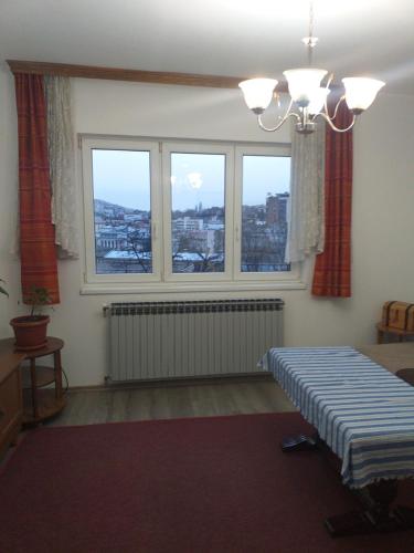 ein Zimmer mit zwei Fenstern und einem Bett darin in der Unterkunft Apartman Sanin in Sarajevo