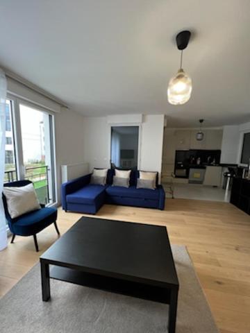 un salon avec un canapé bleu et une table basse dans l'établissement Bel Appart 6/8 p - à 5 min Disney Land, à Chessy