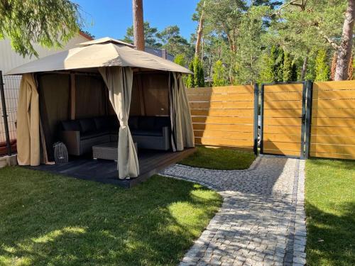a gazebo with a couch under it in a yard at Jodłowy Zakątek NEW in Niechorze