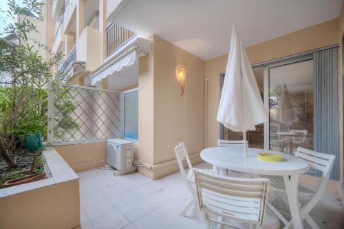 une terrasse avec une table blanche, des chaises et un parasol dans l'établissement Super Central Cannes - all comfort - Calm, à Cannes