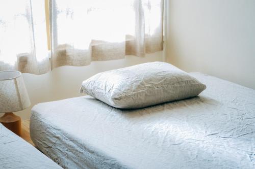 a bedroom with a bed with a pillow and a window at 石打丸山スキー場から徒歩30秒フルリノベの一棟貸切お宿 in Seki