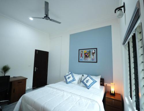 a bedroom with a large white bed with blue walls at AVANTI CASTELLO in Guruvāyūr
