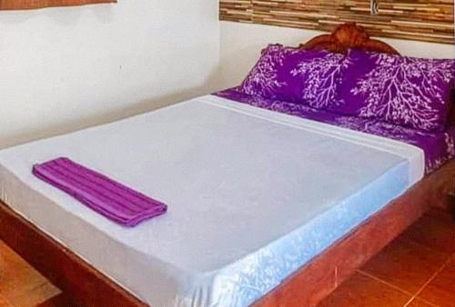 Una cama con almohadas moradas encima. en RedDoorz @ Alcala Garden Resort, 