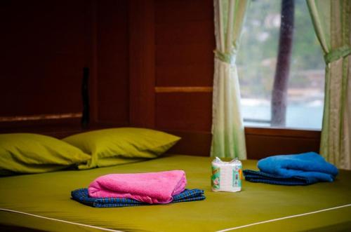 a bed with two towels on it with a window at OK2 Mamajim Bungalows in Koh Tao