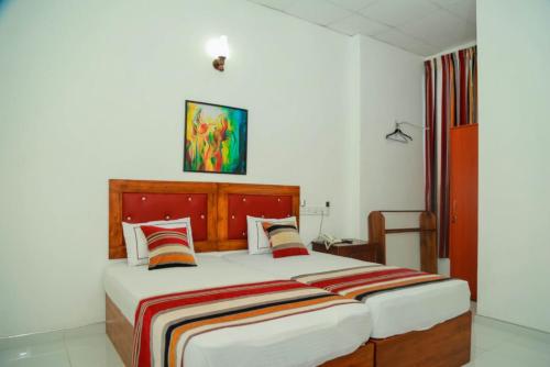 a bedroom with a large bed with a wooden headboard at Hotel MOONSTONE in Anuradhapura