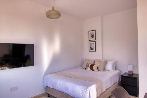 una camera con letto, lenzuola bianche e TV di Phaedrus Living: City Flat Palas 101 a Paphos