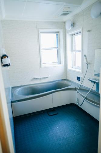 a bathroom with a bath tub and a window at 石打丸山スキー場から徒歩30秒フルリノベの一棟貸切お宿 in Seki