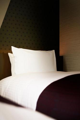a bedroom with a bed with white sheets and pillows at Hotel Intergate Tokyo Kyobashi in Tokyo