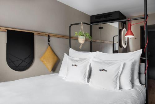 een slaapkamer met een wit bed met witte kussens bij Stay KooooK Bern City - Online Check In in Bern