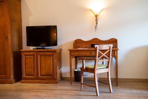 a desk with a television and a chair in a room at Sporthotel Radstadt in Radstadt