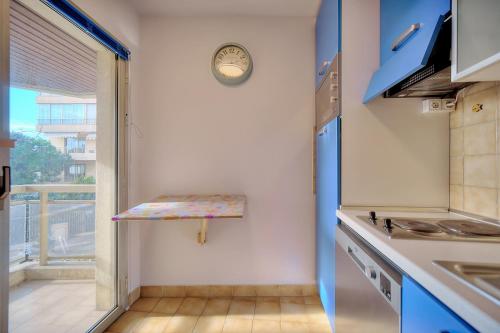 une cuisine avec des placards bleus et une horloge murale dans l'établissement Very pleasant 2 room apartment with garage close to the beaches, à Cannes