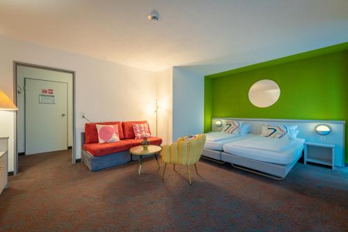 Hessenland Hotel Kassel Innenstadt by Stay Awesome في كاسيل: غرفة نوم بسرير وجدار أخضر