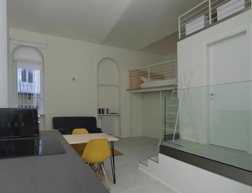 Cette chambre comprend un bureau et une table avec des chaises jaunes. dans l'établissement Il loft sotto la Mole, à Turin