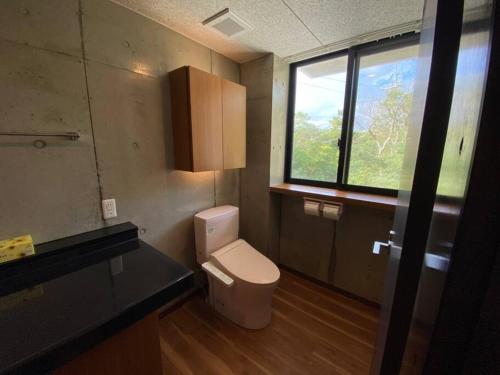 a bathroom with a toilet and a window at Mon Refuge Prive 屋上露天風呂のある隠れ家 in Motobu