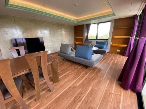 a living room with a table and a couch at Mon Refuge Prive 屋上露天風呂のある隠れ家 in Motobu