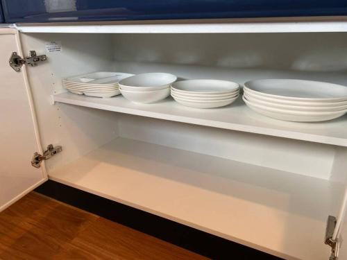 a shelf with white plates and bowls on it at Mon Refuge Prive 屋上露天風呂のある隠れ家 in Motobu