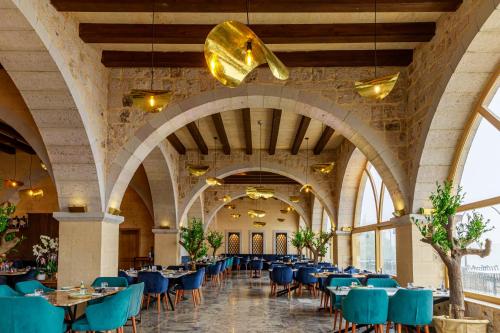 a dining hall with tables and blue chairs at Millstone Cave Suites Hotel in Uchisar