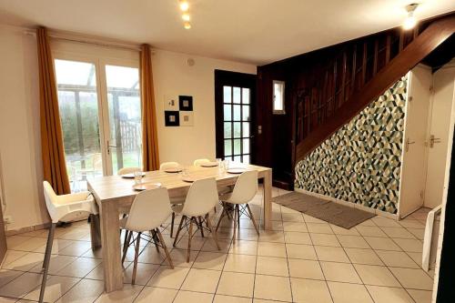 a dining room with a wooden table and white chairs at Charming house near the sea in Courseulles-sur-Mer