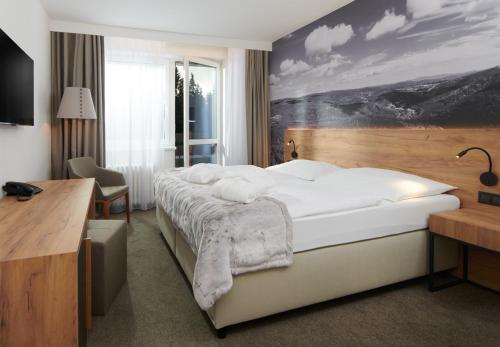 a bedroom with a large bed with a painting on the wall at Wellness Hotel Svornost in Harrachov