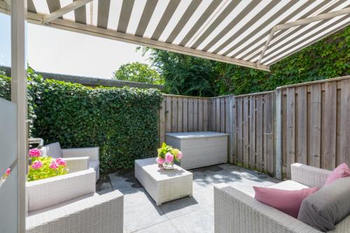 a patio with a pergola and chairs and a table at Vakantiewoning Domburg dichtbij strand, Kanonweistraat 12a in Domburg