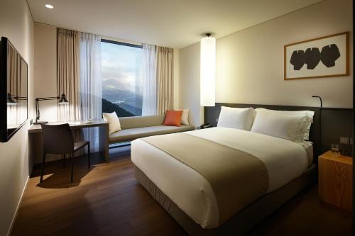 a hotel room with a bed and a couch and a window at Shilla Stay Jeju Airport in Jeju